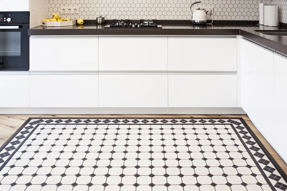 Cuisine moderne avec îlot central, façades blanches laquées sans poignées et plan de travail gris anthracite