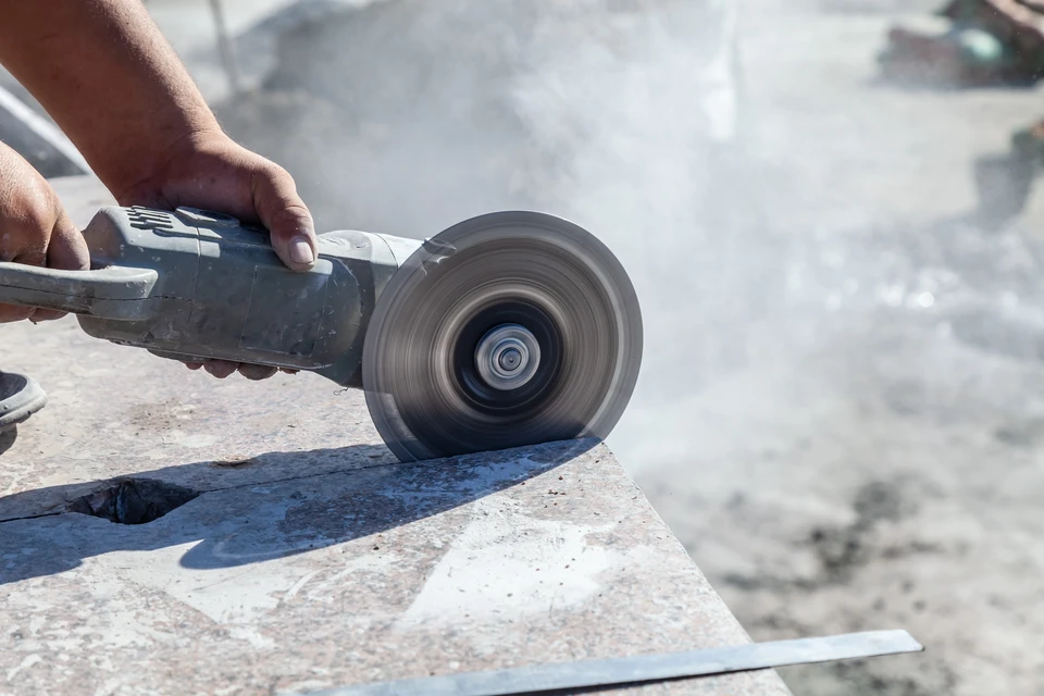 Atelier intérieur avec lame de scie circulaire au premier plan, environnement de travail flou en arrière-plan avec éclairage naturel