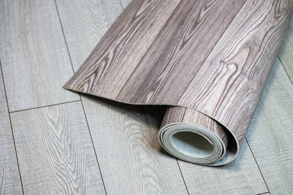 Femme vue de dos dans un environnement intérieur neutre, main posée sur l'épaule droite dans un geste d'auto-massage ou d'étirement